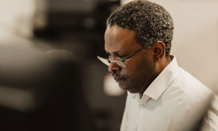 Our team member Genius wearing glasses looking down at a computer screen.