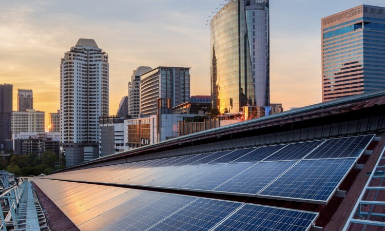 skyline with office buildings in the background and solar panels on a roof in the foreground